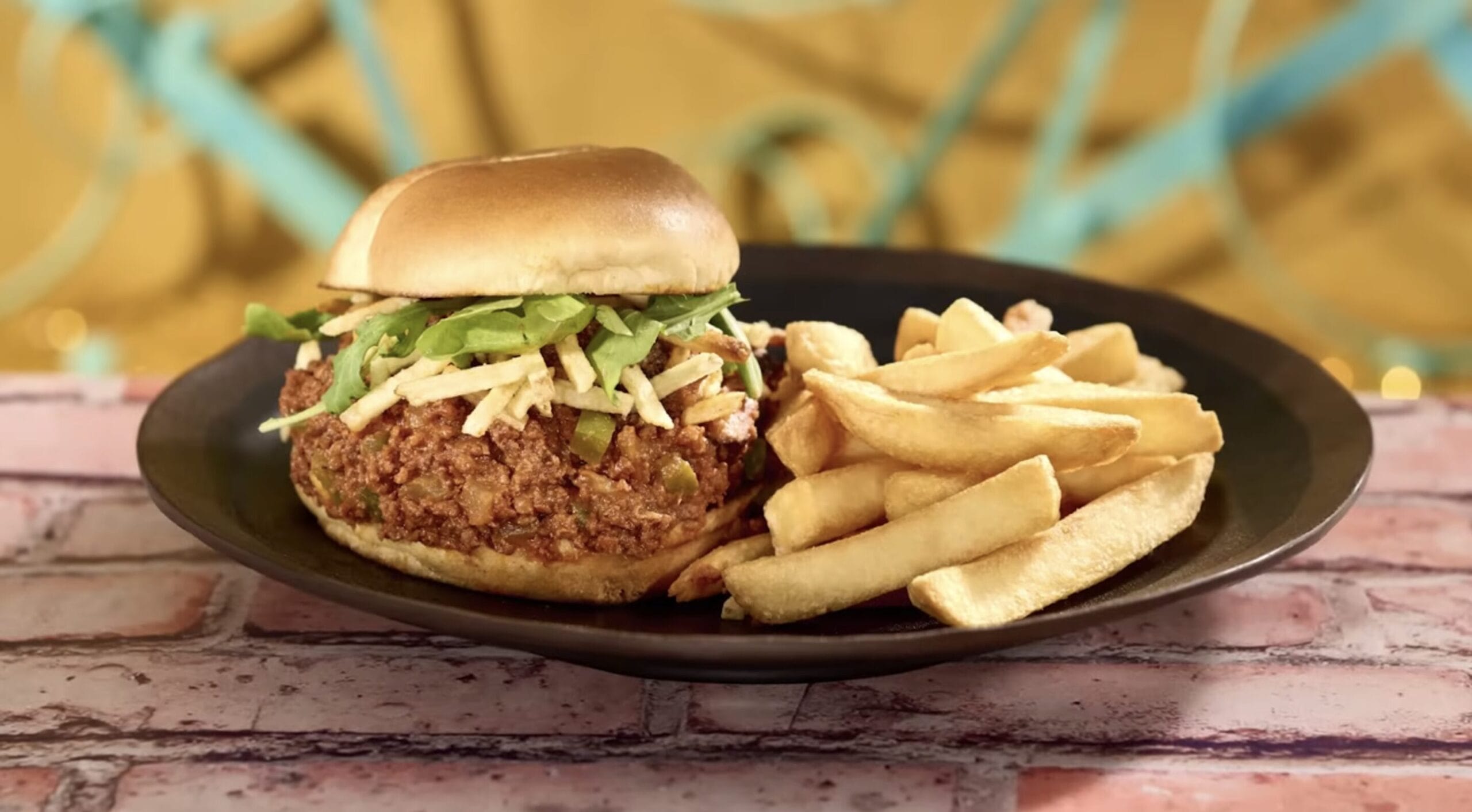 A burger with shredded lettuce and melted cheese, served with thick-cut fries on a black plate, showcases the finest in Food & Beverage. The background features blurred, abstract blue and yellow elements for an epic universe vibe.